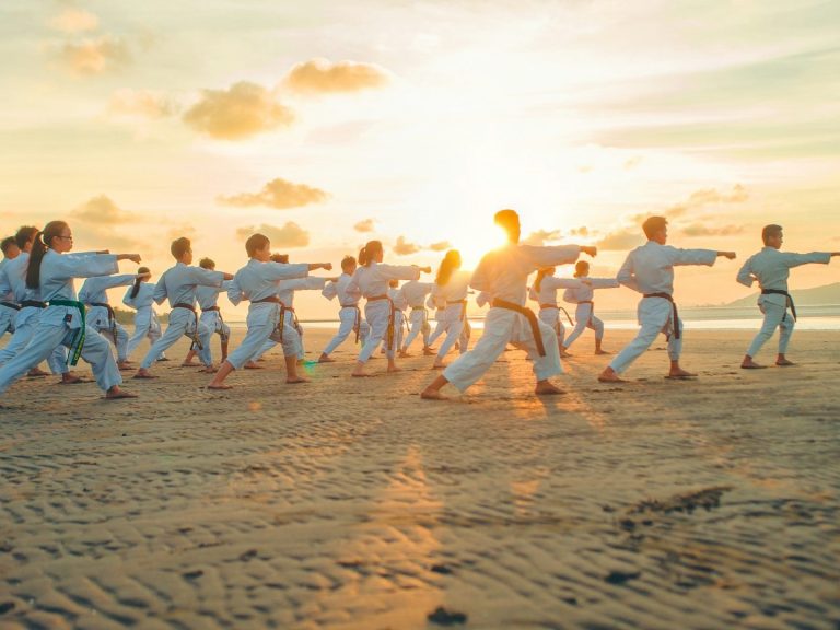 Taekwondo in einer Gruppe am Strand bei Sonnenuntergang.
